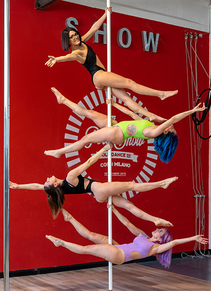 Studenti che eseguono una coreografia di pole dance in uno spazio luminoso e moderno presso The Pole Show a Milano, dimostrando forza e agilità.